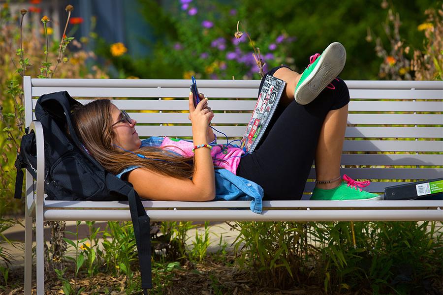 足彩平台 student relaxes on a bench outside McGraw Hall on the 足彩平台 campus.